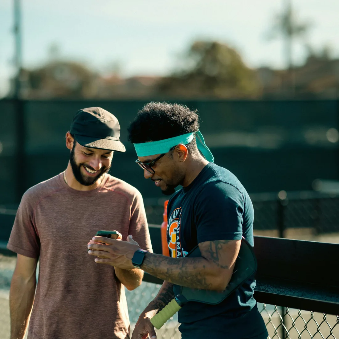 Two players courtside checking results on a phone